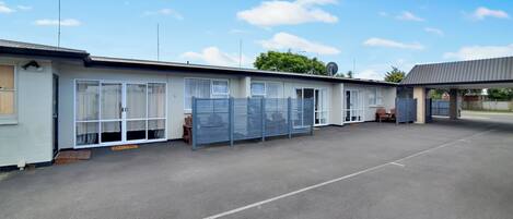Une rangée de maisons mobiles de plain-pied, dotées de grandes fenêtres et d’un espace de stationnement couvert.