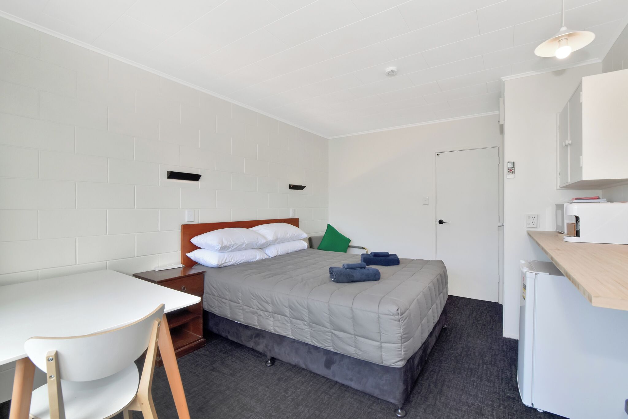 Ein Hotelzimmer mit einem Bett, einem Schreibtisch, einem Sessel, einem kleinen Kühlschrank und einer Mikrowelle.