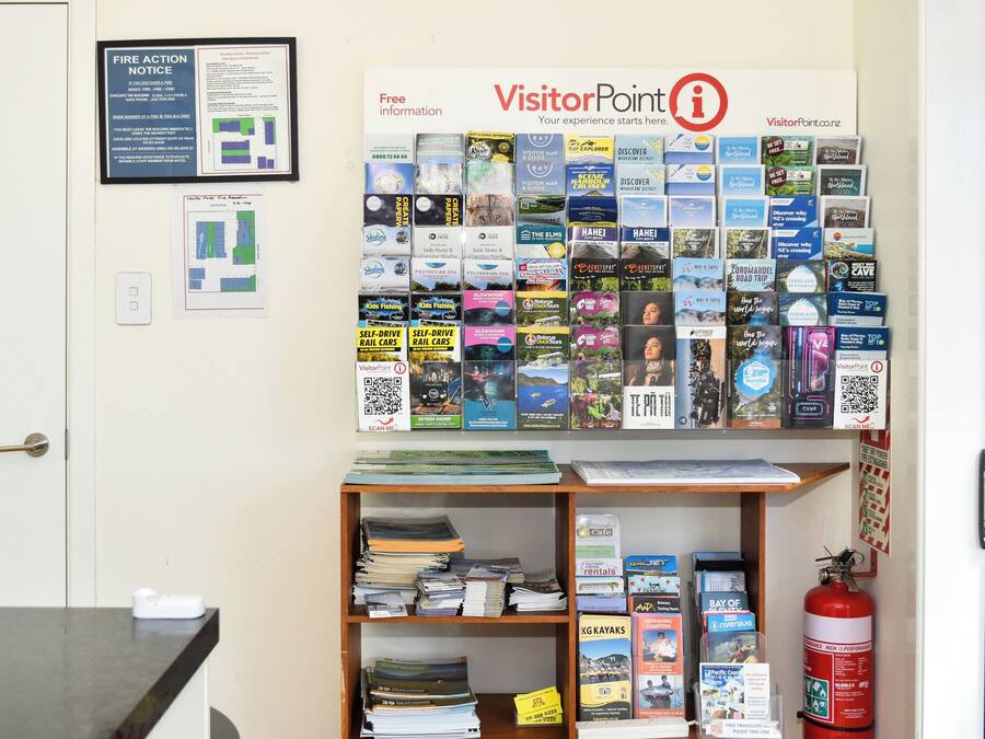 A bulletin board with various travel brochures and a fire action notice.