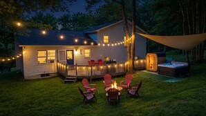 Ein Haus mit Terrasse, Sitzgelegenheiten im Freien, Whirlpool und Lichterketten.