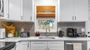 Eine moderne Küche mit weißen Schränken, einem Backofen, einer Spüle und einer Kaffeemaschine.