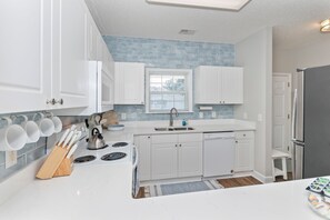 A modern kitchen with white cabinets, a stainless steel stove, and a blue-tiled backsplash. - 2 BR Barefoot Resort Getaway - Free Shuttle to Beach - 2 Pools  (North Myrtle Beach)