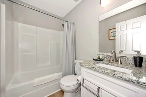Une salle de bain équipée d’une douche, de toilettes, d’un lavabo et d’un miroir.