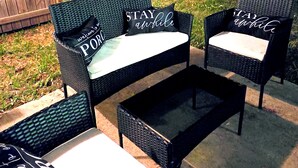 An outdoor seating area with wicker furniture and cushions, a wooden fence in the background, and a dark night sky. - Modern 2BR/2BA Home. Large Backyard. 5 Gig Fiber. Nr VBC, Arsenal & Space Center (Huntsville)