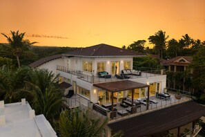 Uma casa de dois andares com varanda, janelas amplas e vista para a paisagem ao redor.