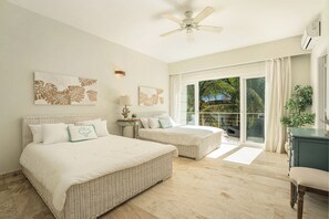 Quarto com duas camas, um ventilador de teto e vista para o exterior.