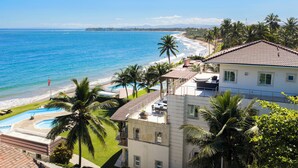 A beachfront property with a swimming pool, a patio, and a view of the ocean. - Beachfront Luxury Penthouse w/ Ocean Views (Cabarete)