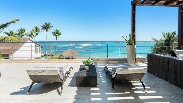 A patio with wicker furniture, a potted plant, and a view of the ocean. - Beachfront Luxury Penthouse w/ Ocean Views (Cabarete)