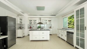 A modern kitchen with white cabinetry, a central island, and a stainless steel refrigerator. - Beachfront Luxury Penthouse w/ Ocean Views (Cabarete)