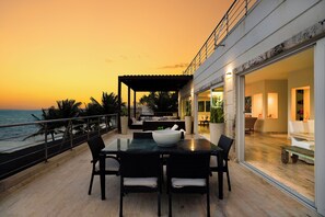 Terraço com mesa, cadeiras e uma tigela. Possui um guarda-corpo na extremidade e oferece vista para um corpo d'água.
