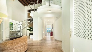 A spacious hallway with a curved reception desk, a staircase, and a view of the outdoors. - Beachfront Luxury Penthouse w/ Ocean Views (Cabarete)