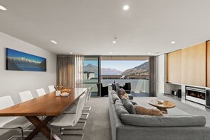 Ein modernes Wohnzimmer mit einem großen Esstisch aus Holz, grauen Sofas und einem Kamin.