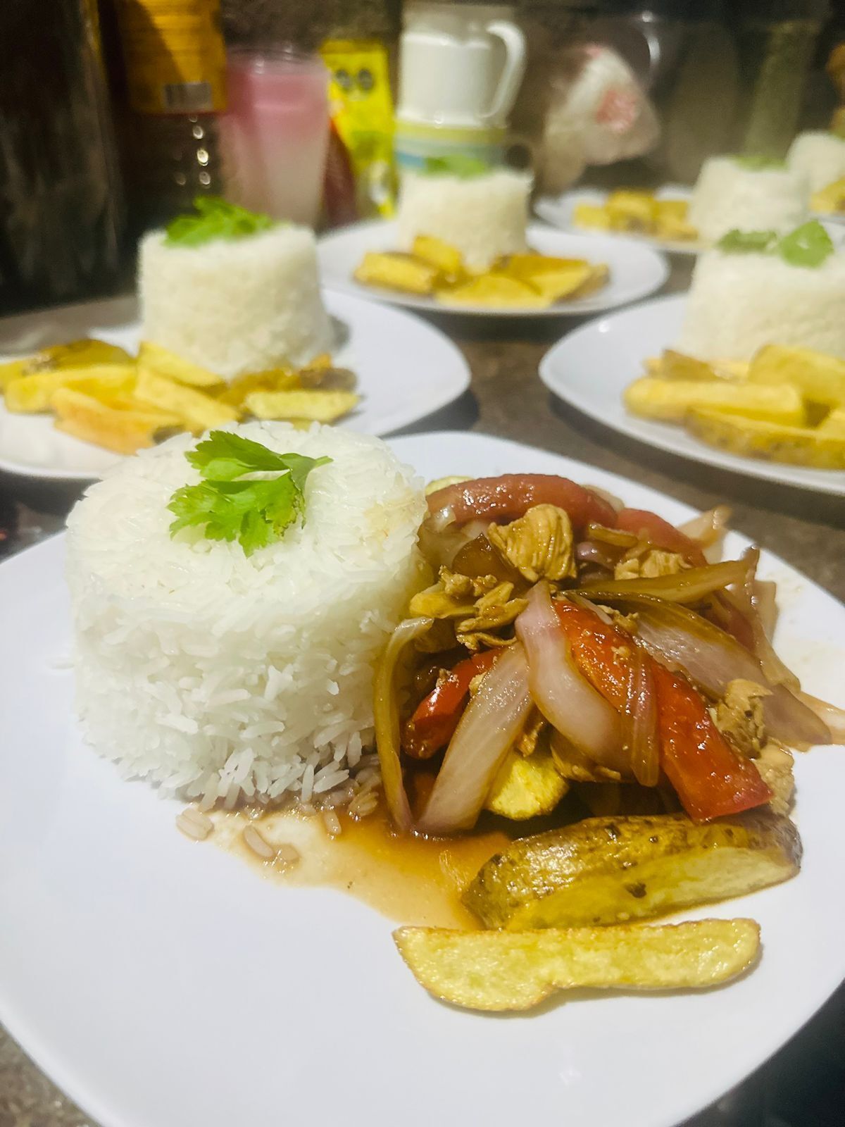 Prato com arroz branco coberto por uma folha, acompanhado de legumes salteados e um item frito, possivelmente peixe ou carne.
