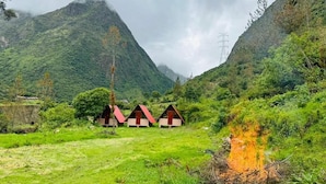 A mountainous landscape with three small cabins with red roofs. - Salakantay glamp (Santa Teresa)
