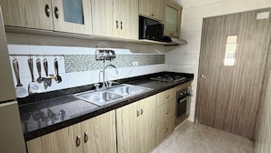 Una cocina con armarios de madera, encimera negra, un lavabo y una estufa.