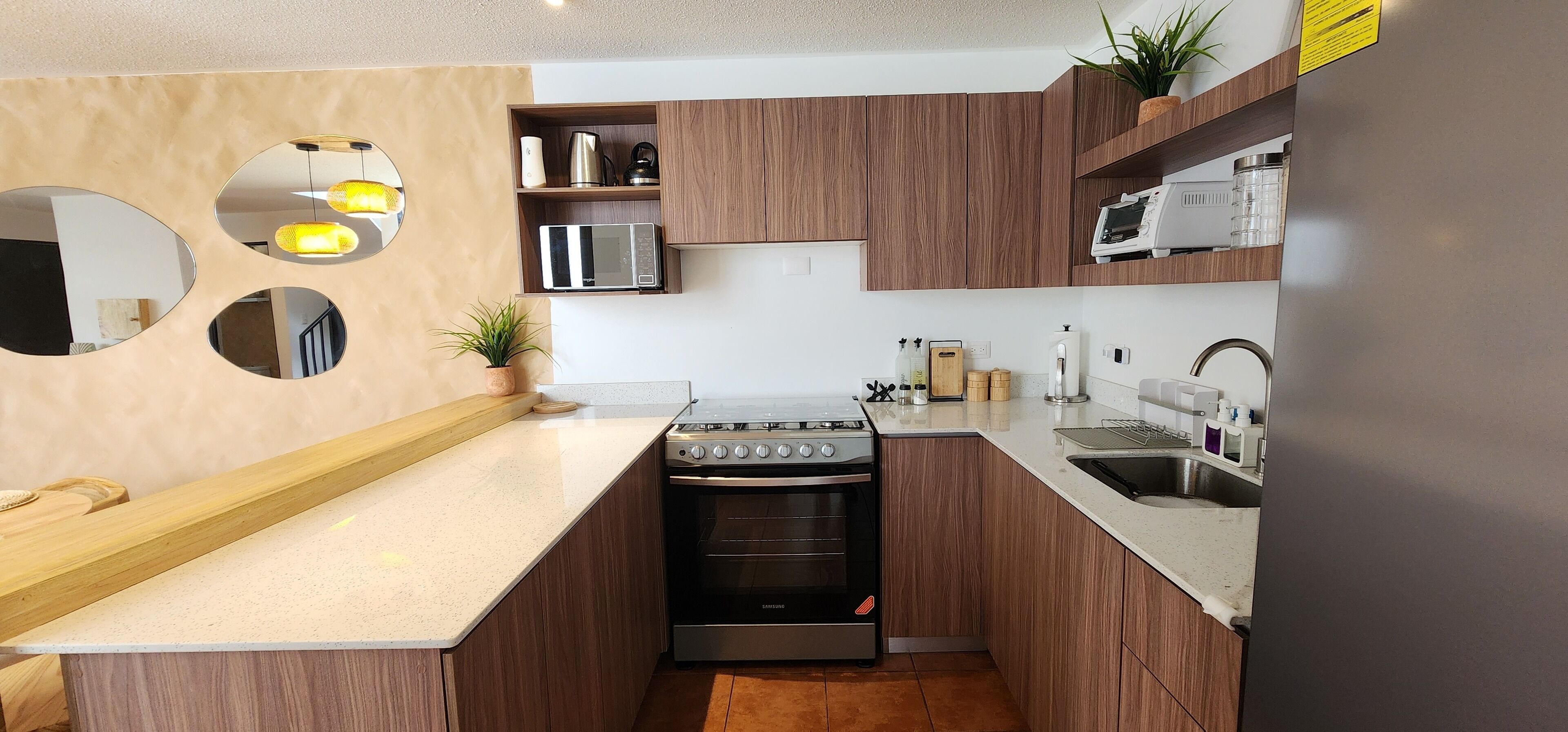 Una cocina moderna con armarios de madera, estufa de acero inoxidable, microondas y un lavaplatos.