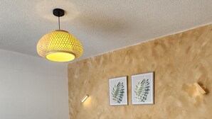 Un dormitorio con cama, mesita de noche, repisa en la pared y lámpara colgante.