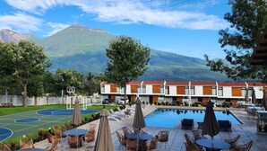 Un hotel con cancha de baloncesto, piscina exterior y vistas a la montaña.