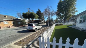 Un carrer residencial amb tanca blanca de palets, gespa i cases.