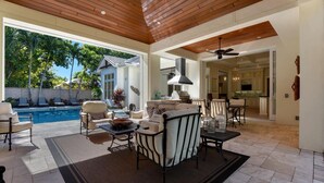 A spacious outdoor living area with a pool, comfortable seating, and a view of a house. - Elevated Coastal Living | Luxury 4BR Home + Den | Designed for the Perfect Getaway (Naples)
