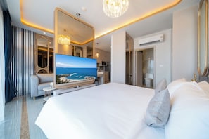 Ein modernes Hotelzimmer mit einem großen Bett, einem Flachbildfernseher, einem Spiegel, einer Kristallleuchtre und Blick auf das Meer.