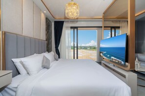 A modern hotel room with a large bed, a television, and a view of the ocean. - Apartment in Laguna Perfect Location (Choeng Thale)