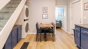 Una cocina con una mesa de comedor, sillas y una escalera que lleva a un área de lavandería.