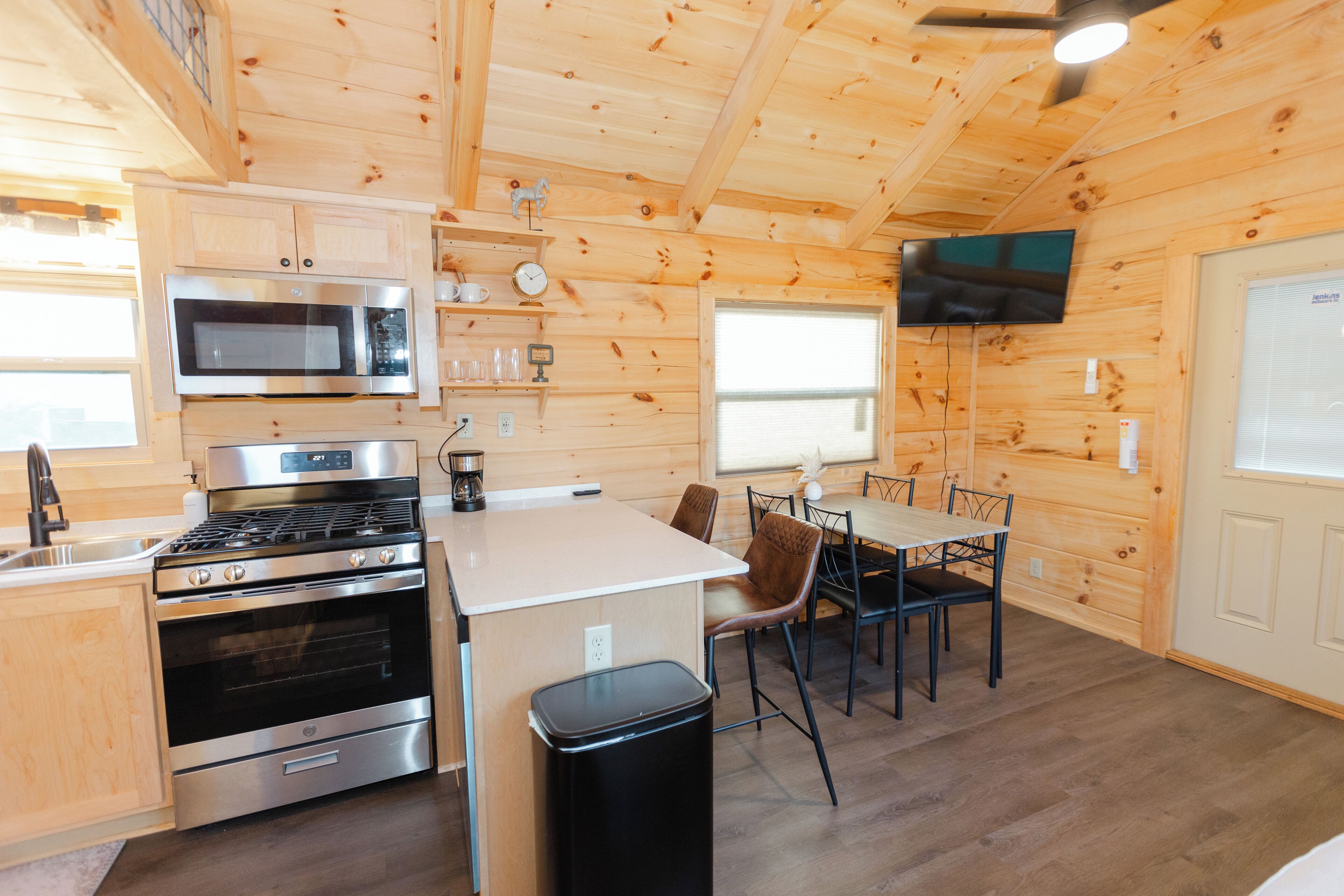 Cocina compacta con microondas, estufa, horno y una pequeña zona comedor con mesa y sillas.