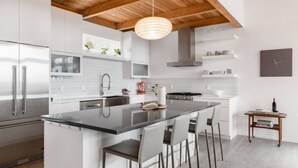 A modern kitchen with a central island, stainless steel appliances, and a wooden ceiling. - Private Luxe Mountain View Getaway (Candler)
