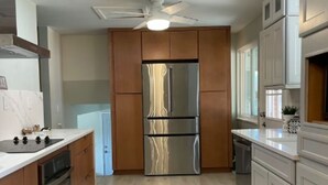 Una cocina moderna con gabinetes de madera, electrodomésticos de acero inoxidable y piso de tonos claros.