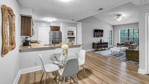 A modern kitchen with a central island, white chairs, and a dining table. - Your Home in Fort Lauderdale: Modern 2BR Stay (Fort Lauderdale)