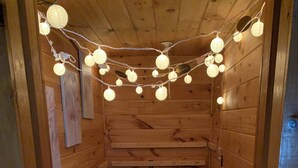 A cozy cabin interior with wooden walls, a small desk, and bean bags. - Gathering Home on Phillips Lake en route to Acadia-New Heat pumps (Dedham)