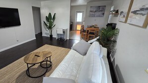 Una sala de estar moderna con un sofá blanco, una mesa de centro de madera y una planta grande en maceta.