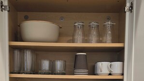 Una cocina con mostrador de madera, un tostador y un armario con vajilla y utensilios.