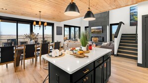 Una cocina moderna con una isla grande, techo de madera y ventanas amplias que ofrecen una vista.