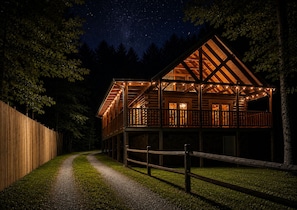 Eine Holzhütte mit einem Balkon, umgeben von Bäumen, bei Nacht.