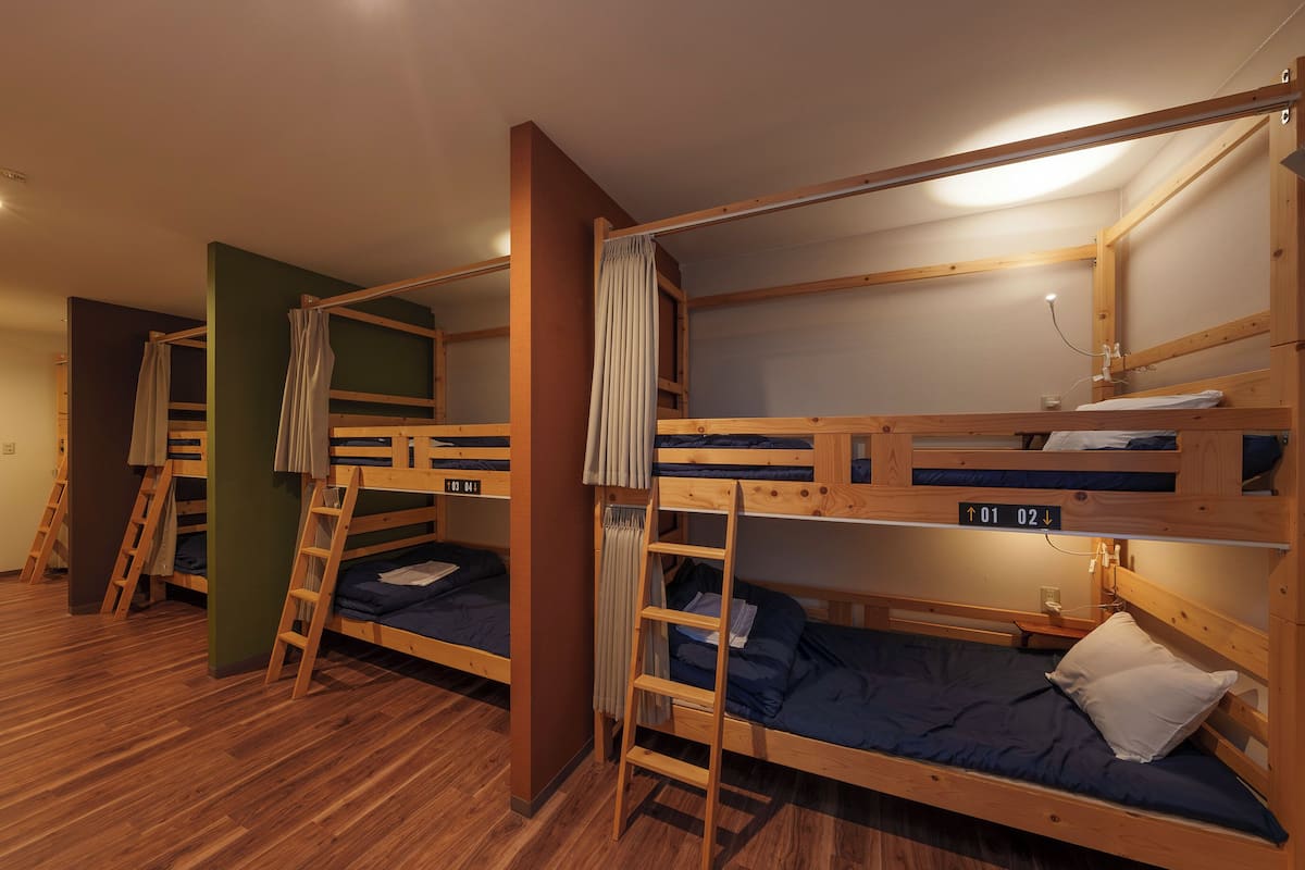 Une chambre de dortoir avec des lits superposés, un plancher en bois et une échelle.