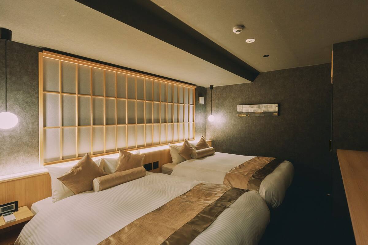 A modern hotel room with a large bed, a nightstand, a wall-mounted light, and a ceiling light.