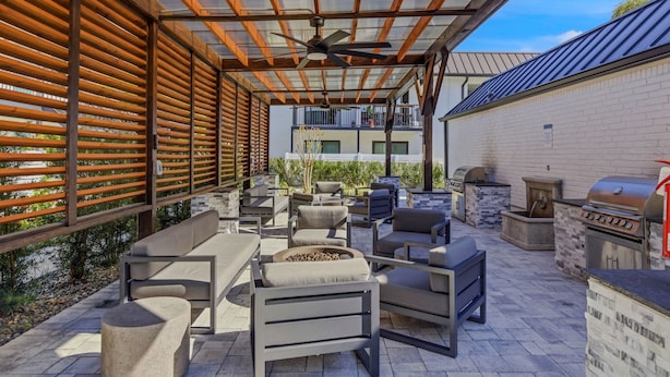 An outdoor patio with seating, a grill, and a view of a building in the background. - Stylish Furnished 2BR in South Tampa | King Bed, Pool (Tampa)
