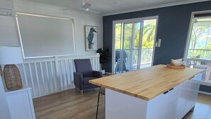 Une cuisine spacieuse dotée d’un grand îlot central, de planchers en bois et offrant une vue sur l’extérieur grâce à de grandes fenêtres.