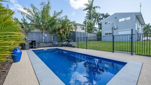 Une piscine rectangulaire à l’eau d’un bleu limpide, entourée d’une terrasse en béton.