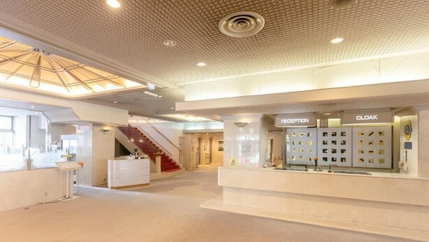 Un vestíbulo amplio con mostrador de recepción, una escalera y un guardarropa.