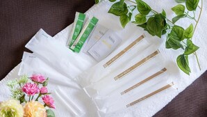 Toalla blanca con artículos de aseo como maquinillas, cepillos de pelo y cepillos de dientes, junto con un pequeño ramo de flores.