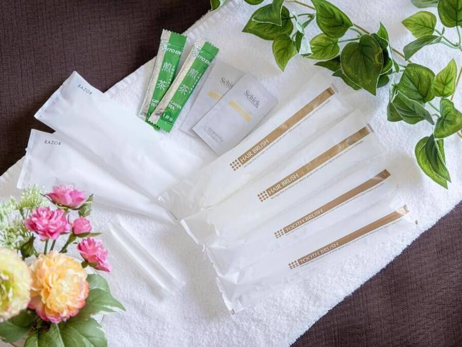 A white towel with toiletries including razors, hairbrushes, and toothbrushes, alongside a small bouquet of flowers.