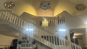 A staircase with a sign that reads "BE OUR GUEST" leading to a landing area with a bar and seating. - Deland Dome Home- 98" TV - Open Kitchen (DeLand)