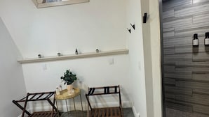 A room with a skylight, a wooden bench, a small table with a plant, and a wall-mounted shelf with potted plants. - Deland Dome Home- 98" TV - Open Kitchen (DeLand)