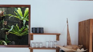 Une cuisine avec des meubles de rangement en bois, un évier, un distributeur d’eau et une étagère où sont posés des verres et un objet décoratif.