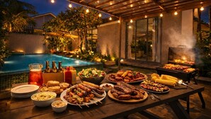 Un espace extérieur aménagé pour les repas, avec une piscine, un coin barbecue et une variété de plats proposés.