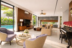 A modern living room with a pool view, a piano, and a kitchen area. - Sam Villa Riverside – Private Pool Villa Da Nang (Đà Nẵng)
