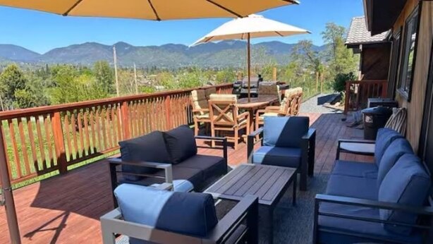 Een terras met buitenmeubilair, waaronder banken en tafels, met uitzicht op een bergachtig landschap.